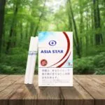 ซองบุหรี่ Asia Star Cafe สีขาวคาดแถบสีแดงและฟ้า พร้อมโลโก้ Iced Coffee วางบนโต๊ะไม้ฉากหลังป่า