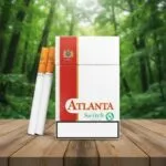 ซองบุหรี่ Atlanta Switch Menthol สีขาวแถบแดง พร้อมมวนบุหรี่วางบนโต๊ะไม้ในบรรยากาศป่า